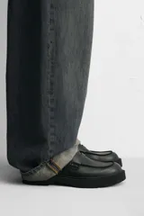 Mocasín de cuero color marrón oscuro, con antifaz y suela track de goma negra.