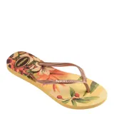 Sandalias Havaianas Slim Tropical, con base estampada con motivos florales en tonos amarillos, naranjas y verdes, y tiras finas color bronce.