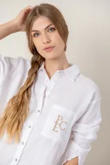 Camisa de lino color gris claro con bordado de monograma PEC en el bolsillo.