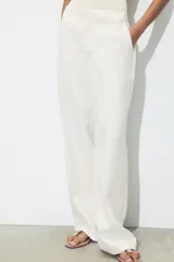 Pantalón de tiro alto color fucsia, con bolsillos delanteros y falsos bolsillos de vivo en la espalda. Tejido con efecto arrugado, pernera recta y cierre frontal con cremallera, botón interior y gancho.