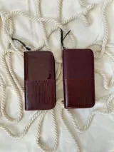 Billetera grande de cuero color borgoña, con cierre metálico y logo de la marca grabado. Incluye moneda colgante plateada con el logo de la marca.