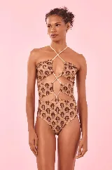 Traje de baño enterizo color beige con estampado de figuras geométricas en marrón, escote recto con tiras finas cruzadas y aberturas en la cintura.