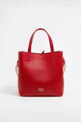 Bolso rojo de cuero vacuno con doble asa de mano, correa de tela ajustable y extraíble, tres compartimentos internos, bolsillo interior con cremallera, cierre con cinta de piel y logo metálico de la marca.