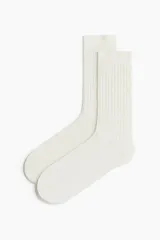 Par de medias de caña media color blanco, tejidas en punto acanalado con borde superior elástico.
