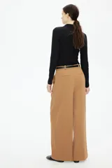 Pantalón ancho color marrón claro con pinzas, bolsillos laterales y trabillas para cinturón.