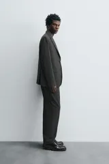 Pantalón de vestir de corte slim fit, color gris oscuro con micro estampado a cuadros. Cuenta con bolsillos laterales y traseros de doble vivo con botón. Cierre frontal con cremallera y botón.