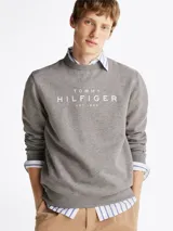 Buzo gris de Tommy Hilfiger con cuello redondo, corte regular y hombros ligeramente caídos. Presenta el logo de la marca estampado en el pecho y un logo bordado en el puño.