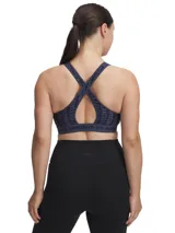 Top deportivo Under Armour con estampado floral en tonos rosa y amarillo sobre fondo negro. Cuenta con tirantes cruzados en la espalda y banda elástica con el logo de la marca en el contorno inferior.