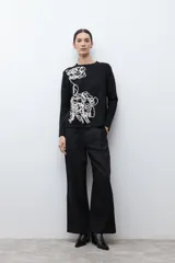 Sweater color rosado melange con cuello redondo y manga larga. Presenta un bordado abstracto en color crema en la parte frontal.