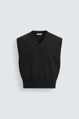 Chaleco negro de punto con cuello en V, corte cropped y sisas anchas.