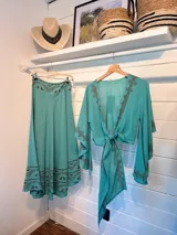 Pollera larga color celeste con estampado de guardas geométricas en color marrón en la cintura y el ruedo. Corte amplio y fluido.