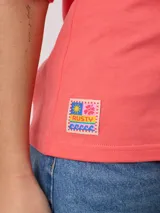 Remera color crudo de corte oversized con estampado de palmeras, flores y texto 'California' y 'Rusty Tribe'.