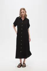 Vestido camisero midi negro de corte holgado, con cuello camisero, mangas cortas con trabillas, cierre frontal con botones, bolsillo en el pecho y bolsillos laterales.