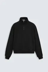 Sudadera negra de algodón con cuello alto y cierre de cremallera frontal. Corte relaxed fit, manga larga y terminaciones en rib.