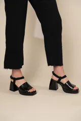Sandalias negras de cuero con plataforma y taco cuadrado. Tiras anchas sobre el empeine y pulsera al tobillo con hebilla.