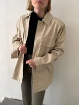 Sobrecamisa negra de ecocuero con cuello clásico, cierre frontal con botones a presión, mangas largas con puños abotonados, dos bolsillos de parche con solapa en el pecho y corte recto.
