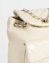Mochila negra de cuerina acolchada con diseño de líneas diagonales. Tiene solapa con broche decorativo y botón para cerrar. Cuenta con correas regulables, manija superior de material principal y metal, y tira de ajuste de metal.