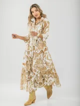 Vestido largo camisero con estampado floral en tonos beige y blanco, con cuello camisero, mangas 3/4 y falda escalonada. Incluye cinturón de soga con hebilla de madera.