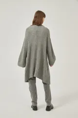 Saco largo de tejido de punto grueso color gris, con mangas largas y bolsillos frontales. Diseño holgado y sin cierre.