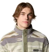 Buzo polar Columbia de hombre con estampado de camuflaje en tonos beige, gris y verde. Tiene cuello alto con cierre de botones a presión, bolsillo en el pecho con cierre de cremallera y logo de la marca bordado.