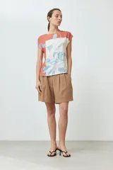 Blusa sin mangas con estampado floral en tonos celeste y naranja sobre fondo blanco. Presenta cuello redondo y corte recto.