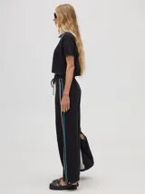 Pantalón de algodón negro, corte holgado y pierna ancha con pretina elástica. Presenta rayas bicolor al costado en blanco y celeste. Calce de tiro alto.