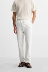 Pantalón de jogging color beige confeccionado en tejido de mezcla de algodón. Cuenta con cintura elástica ajustable con cordón, bolsillos frontales y traseros.