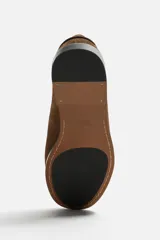 Mocasín color marrón de cuero con acabado serraje, antifaz, horma redonda y suela con ligero tacón.