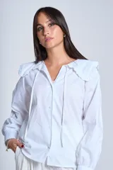 Camisa blanca de manga larga con cuello Claudine y lazos en el escote.