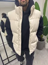 Chaleco puffer color beige de cuerina con cierre frontal.