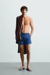 Short de baño azul con cintura elástica ajustable con cordón, bolsillos laterales y bolsillo trasero de plastrón.