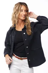 Sobrecamisa de jean color negro con cuello clásico, cierre frontal con botones metálicos, mangas largas con puños abotonados y bolsillos de parche en el pecho.