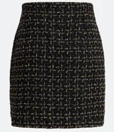 Minifalda negra de tweed con estampado a cuadros en dorado, con tres botones decorativos en el frente y abertura lateral.