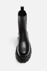 Bota Chelsea de cuero negro con elásticos laterales, tirador trasero y suela track de goma.