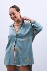 Camisa celeste con bordado de hojas color dorado, de corte holgado y manga larga con puños abotonados.