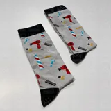 Par de medias grises con puño, talón y puntera negros. Estampado con elementos de barbería: secador de pelo, tijeras, navaja, peine y poste de barbero.