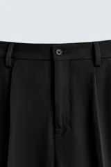 Pantalón negro relaxed fit confeccionado en tejido con viscosa. Cintura con detalle de pliegues en delantero. Bolsillos frontales y detalle de bolsillos traseros de vivo. Cierre frontal con cremallera y botón.