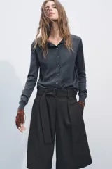 Chaqueta de punto fino color gris oscuro confeccionada con lana. Tiene cuello redondo, manga larga y cierre frontal con botones.