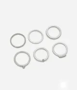 Set de seis anillos plateados de metal con diferentes diseños: uno liso, uno con bolita, uno con detalle de strass, uno con textura, uno con detalle de estrella y uno con hilera de strass.