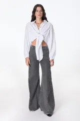 Blusa negra con escote en V, mangas largas abullonadas y lazo para atar en la parte delantera.