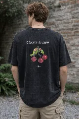 Remera azul con efecto lavado, de corte holgado y manga corta. Estampa trasera con la frase "Cherry Season" y un diseño pixelado de cerezas.