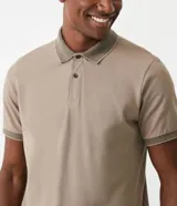 Polo de manga corta color beige, confeccionada en algodón con cuello jacquard y ribete en las mangas.
