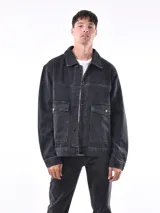 Campera de jean negra con cuello clásico, cierre frontal con botones metálicos, bolsillos con solapa en el pecho y corte recto.