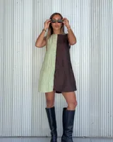 Vestido corto con escote recto, diseño color block en verde claro y marrón, sin mangas y con bolsillos laterales ocultos.