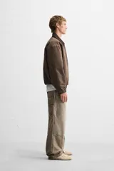 Pantalón color marrón con efecto lavado, corte relaxed fit, cinco bolsillos, aplicación de tira y bolsillo multifunción en perneras, cierre frontal con cremallera y botón.