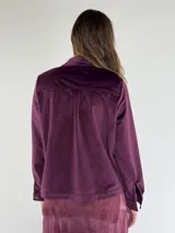 Chaqueta color beige con cuello camisero, cierre frontal con botones, bolsillos de parche con solapa y manga larga.