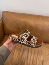 Sandalias con estampado animal print de vaca, con dos hebillas doradas ajustables, plantilla anatómica y suela tipo Birkenstock.