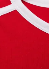 Remera roja de corte recto con cuello redondo y mangas cortas con terminaciones en contraste blanco. Presenta dos líneas blancas paralelas en los hombros.