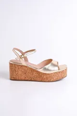 Sandalia dorada con plataforma de corcho, tira delgada sobre los dedos y tobillera con hebilla.
