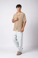 Camisa negra tejida de manga corta, con calado aireado, cuello tipo bowling y botones al tono. Diseño de corte relajado.